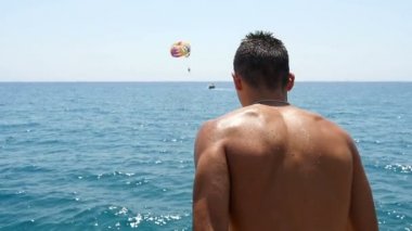 Genç atlet çalışır ve ayak önce slo-mo denize bir platformdan diğerine atlar