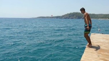 Ağır çekimde yaz aylarında denizin içine düz bir platform gelen dalış genç adam