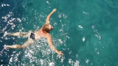 Sarışın genç kadın ağır çekimde yaz aylarında kurbağalama Ege Denizi'nde yüzer