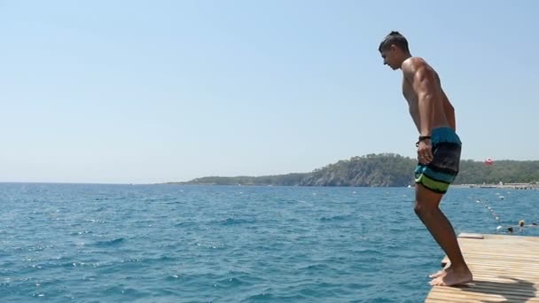 Grote jongen duikt als een snoek van een platform in de Egeïsche zee in slow motion — Stockvideo