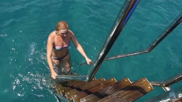 Jonge vrouw klimt de trap en houdt van rails, om uit water in slo-mo — Stockvideo