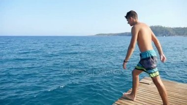 Şortlu genç adam ayak ilk Bizanslılar deniz sularında slo-mo atlar