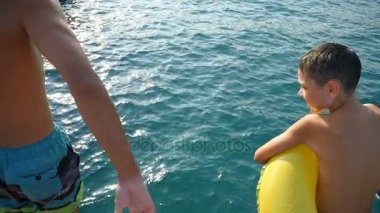 İki kardeş, büyük ve küçük, ayak ilk deniz sularında yaz slo-mo atla