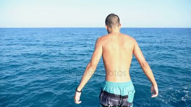 Jonge man in korte broek springt hoofd eerst in de Middellandse zee wateren in slo-mo — Stockvideo