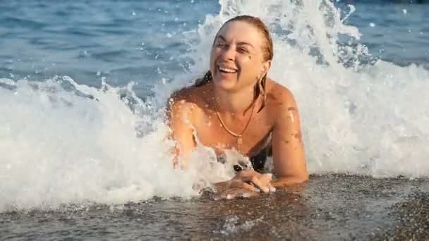 Junge Frau liegt am Strand im aufgeräumten Meerwasser und lacht fröhlich im Slo-mo — Stockvideo