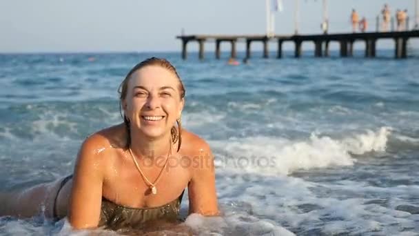 スローモーションで夏の海の海岸の青い海で横になっている若い女性を笑顔 — ストック動画