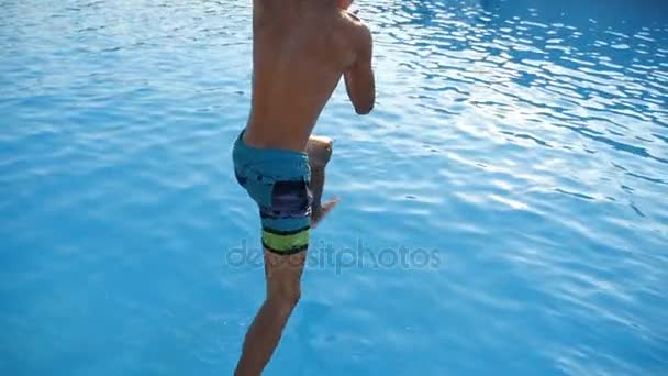 Jonge man springt voeten eerst in de blauwe wateren van de zee in slow motion — Stockvideo