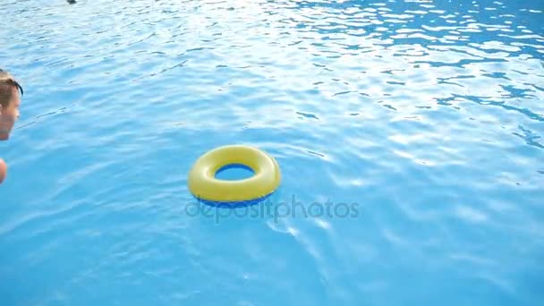 Fiatal férfi egyenesen ugrik felfújható gyűrűt a tenger kék vizében a slo-mo — Stock videók