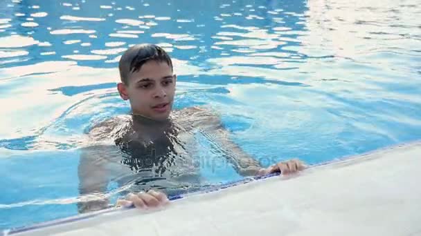 Jeune homme garde le bord d'une piscine étant dans l'eau, profitant de sa vie à Montréal- mo — Video
