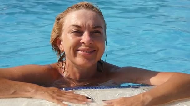 Молода жінка стоїть в басейні і щасливо посміхається в шлю-мо — стокове відео