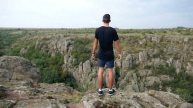 Genç güçlü adam ellerini kenara slo-mo derin bir uçurum yakınındaki bir uçurumun tepesine koyar