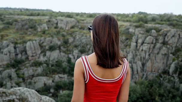 Štíhlá dívka stojí na vrcholu z vysokého útesu v létě v pomalém pohybu — Stock video