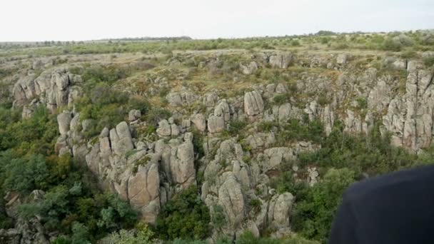 Un joven se encuentra en lo alto de un acantilado mirando pintorescas colinas en slo-mo — Vídeos de Stock