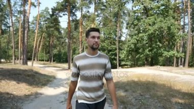 Genç bir beyaz adam bir çam ormanı içinde özgürce yaz yavaş içeri girer