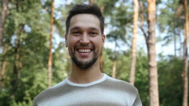 Ağır çekimde yaz aylarında yeşil karışık ormandaki bir neşeli genç adam gülümsüyor