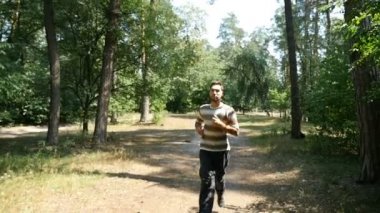 Yavaş çekimde bir ormandaki sportif siyah pantolon şekilde olan genç bir adam çalışır