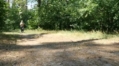 Çizgili bir gömlek ve siyah pantolon genç bir adam bir orman yavaş çalışır