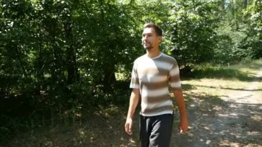 Uzun boylu bir genç adam serbestçe yavaş yaz aylarında yeşil bir ormanda olur
