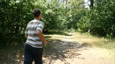 Yavaş çekimde bir ormandaki çizgili gömlek ve siyah pantolon genç bir adam çalışır