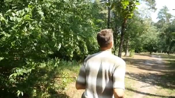 Un homme actif en t-shirt rayé et pantalon noir court dans une forêt au ralenti — Video