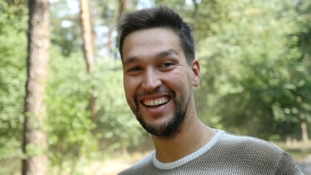 Šťastné vousatý muž úsměvy v borovém lese, v létě v pomalém pohybu — Stock video