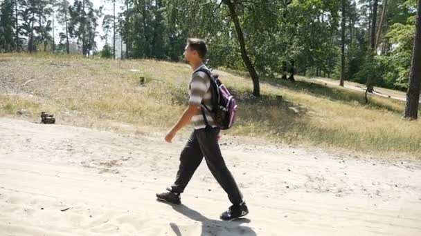 一个随和的人，带背囊上调在一片松树林慢动作的夏天 — 图库视频影像
