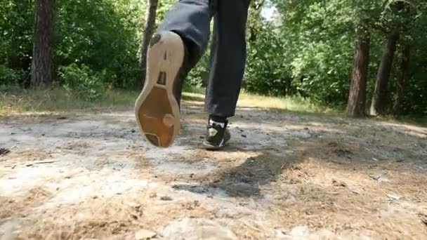 Manliga fötter i svart sneakers börja köra i en skog i slow motion — Stockvideo