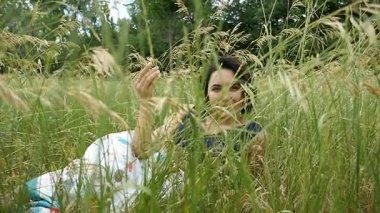 Slo-mo büyük bir çita gibi pitoresk bir çimenlikte romantik bir kadın yatıyor