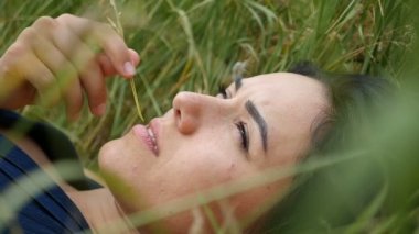 Romantik kız güzel bir çim üzerinde yalan ve thoughfully yavaş çekimde arar