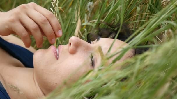 A nice girl lies on a nice lawn and looks up thoughfully in slow motion — Stock Video