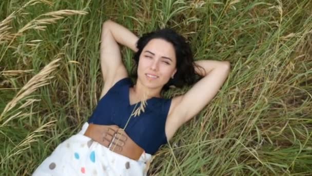 非常漂亮的姑娘躺在绿色的草坪上在慢动作夏季晴朗的一天 — 图库视频影像