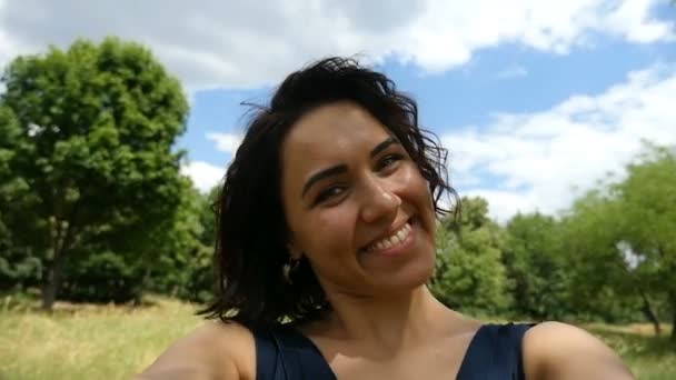 Jonge brunette meisje gelukkig glimlacht en draait van links en rechts in de zomer in slo-mo — Stockvideo