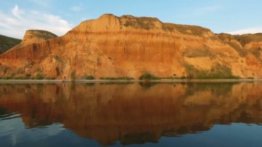 Engebeli sahil üzerinden uçan bir dron yaz aylarında yüksek kırmızı ve kahverengi tepeler