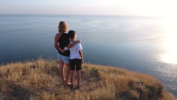 Aerial shot of a mother and her boy standing on a seacoast hill with sagebrush — Stock Video