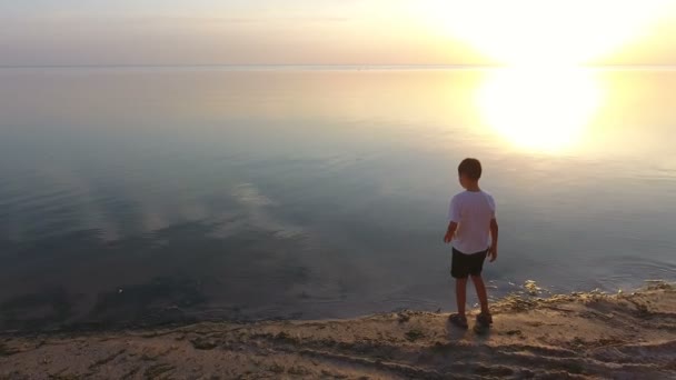Aerial shot of a small boy standing on a seashore and watching the Black Sea — Stock Video