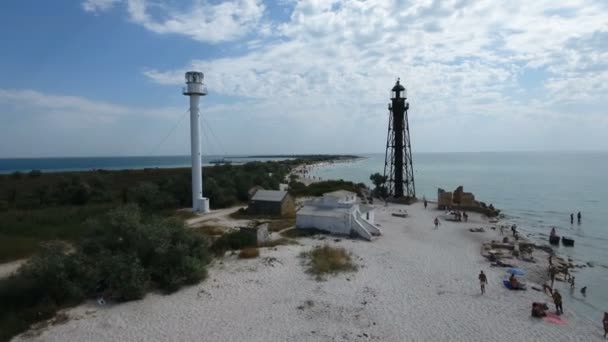 Aerial shot of a white beacon, a black border tower, a small house on a seacoast — Stock Video