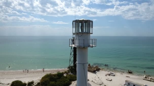 Tiro aéreo de um farol branco alto com nuvens pitorescas no fundo — Vídeo de Stock