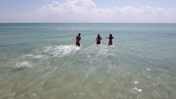 Повітряний постріл трьох молодих людей працює у хвилях Чорного моря влітку — стокове відео