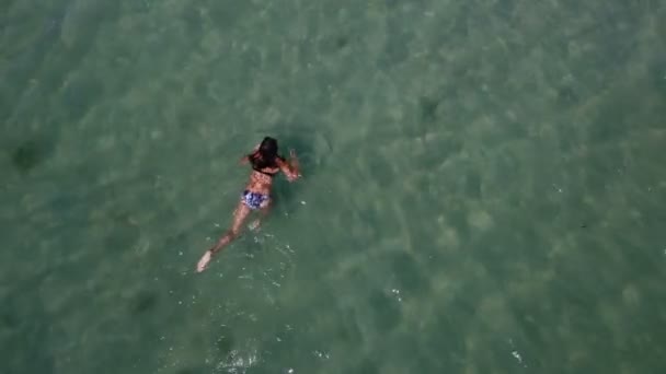 Tiro aéreo de uma menina fina nadando peito nas ondas azuis do mar no verão — Vídeo de Stock