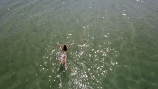 Foto aérea de una chica delgada nadando en las olas azules del mar en verano — Vídeos de Stock