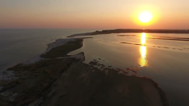 Tiro aéreo de um pôr-do-sol cor-de-laranja na ilha de Dzharylhach cuspo de areia no verão — Vídeo de Stock