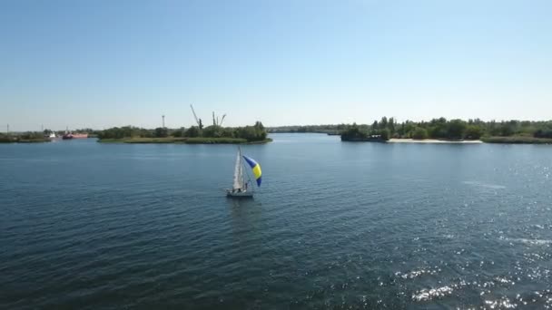 Foto aérea de un yate mástil con una vela azul y amarilla flotando en el Dnipro — Vídeos de Stock