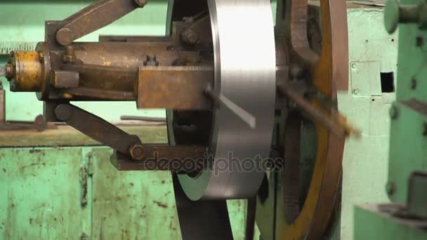 Algumas faixas de metal se estendem de um carretel de metal em uma oficina em uma fábrica — Vídeo de Stock