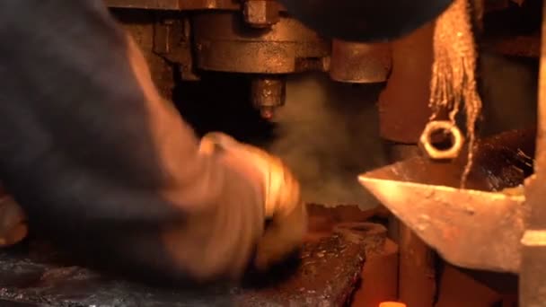 Trabalhador ferreiro usa suas pinças e muda lingotes de ferro vermelho sob prensa de forjamento — Vídeo de Stock