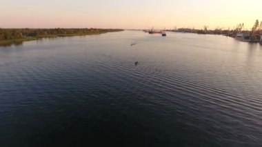 Motorbot üzerinde modern bir port yakınındaki Dnipro yaz aylarında hareketli hava atış. Hızlı bir şekilde motorbot endüstriyel bir port yakınındaki Dnipro pürüzsüz yüzeyi yaz aylarında hareketli nefes kesen bir kuş bakışı. 