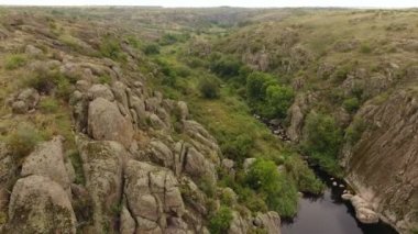    Gizemli bir kuş bakışı bir siyah kahverengi taş Ukrayna ile yüksek tepeler arasında uzanan bir derin kanyon akan nehrin.