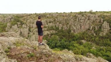 Büyük kahverengi taş ve mutlu bir genç çocuk siyah bir tshirt ve şort üzerine şaşırtıcı bir kuş bakışı tepelik dağların kaplı 