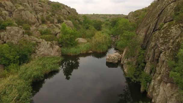 一条弯曲的黑色河流在乌克兰一个狭窄的峡谷中的大石块和岩石之间流动的童话般的景色 — 图库视频影像