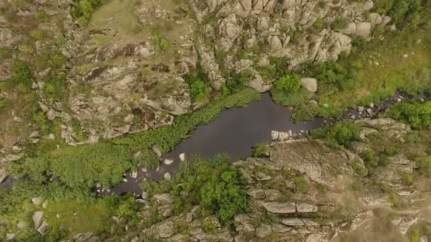   Une vue saisissante d'une étroite rivière noire se déplaçant dans un ravin entre d'anciennes roches brunes couvertes de nombreuses fentes en Ukraine en été ..