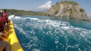 Kemer, Turkey - 19 Temmuz 2017: Mutlu turist Türkiye'de bir motoboat güneşli bir yavaş hareket sonra hareket büyük sarı muz sürme harika bir manzarasını.